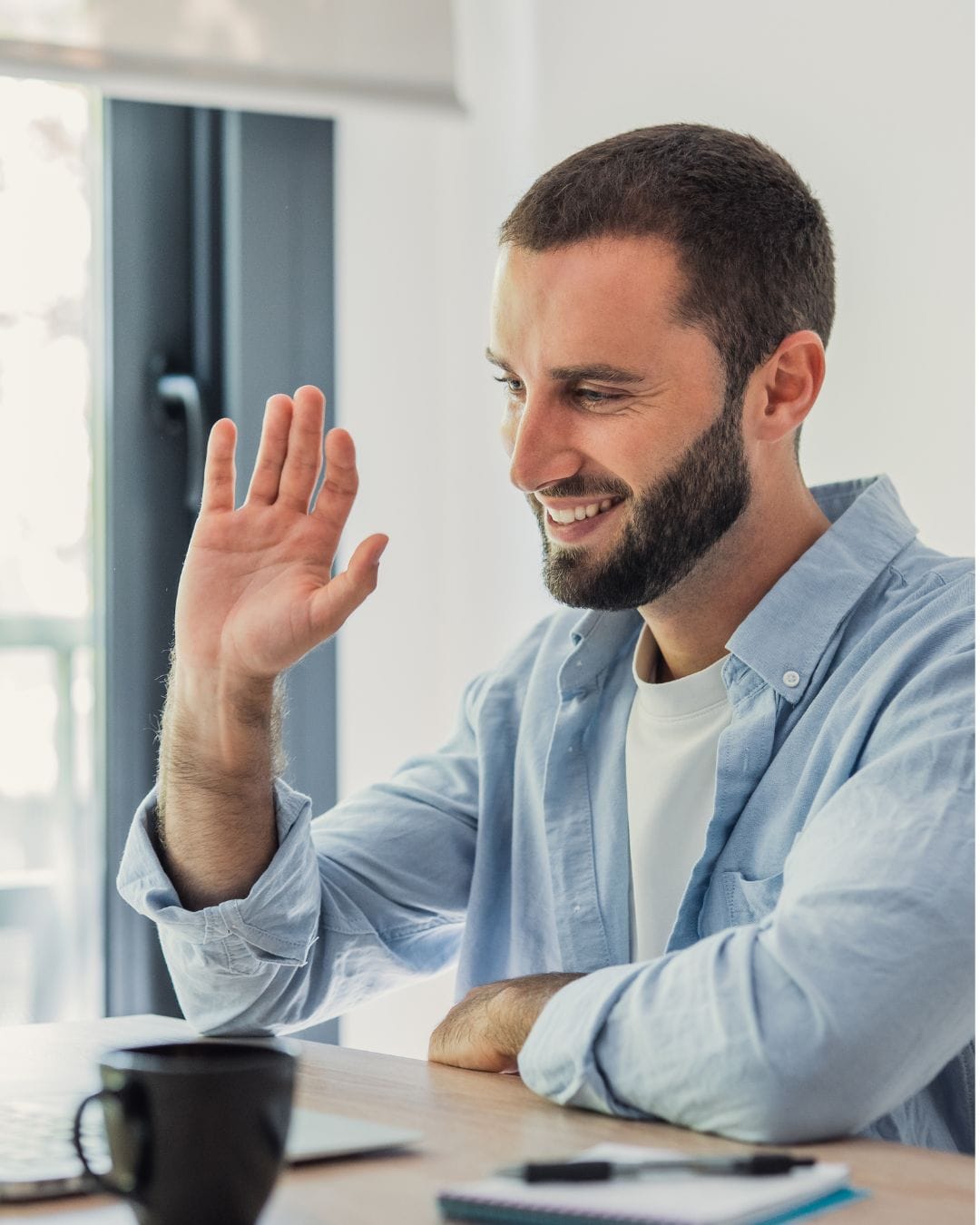 Hombre saludando durante una videollamada, iniciando su sesión con psicólogos online latinos de Sentirem